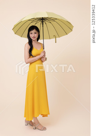 A woman in her 20s wearing a yellow umbrella 125339412