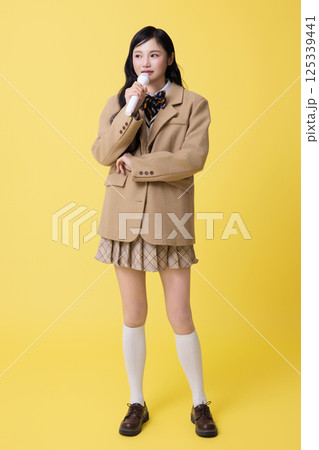 A girl wearing a school uniform and singing with a microphone 125339441
