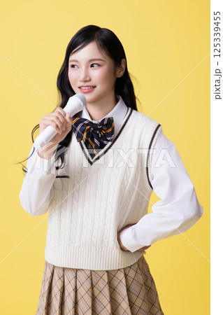 A girl wearing a school uniform and singing with a microphone 125339455