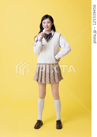 A girl wearing a school uniform and singing with a microphone A girl wearing a school uniform and singing with a microphone 125339456