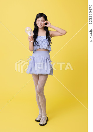 A girl wearing a stage costume and posing with a light stick A girl wearing a stage costume and posing with a light stick 125339479