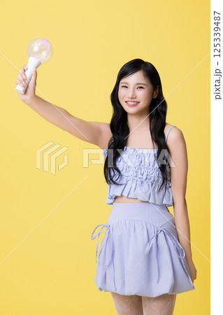 A girl wearing a stage costume and posing with a light stick A girl wearing a stage costume and posing with a light stick 125339487