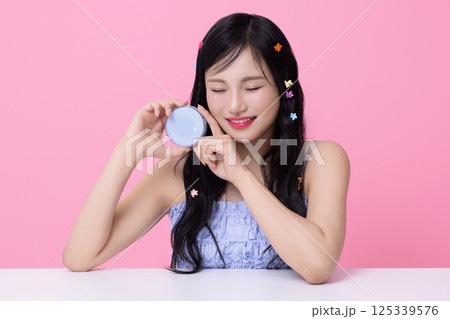 Portrait of young woman posing with cosmetics and wearing pins in her hair Portrait of young woman posing with cosmetics and wearing pins in her hair 125339576