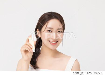 Cropped view of young woman posing with lip balm 125339723