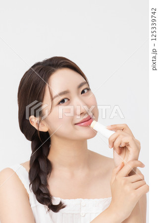 Cropped view of young woman posing with lip balm 125339742