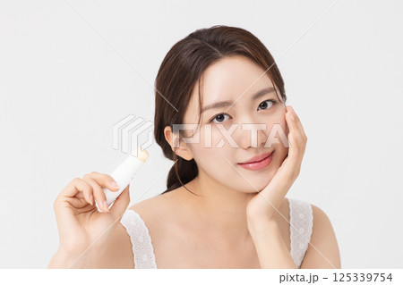 Cropped view of young woman posing with lip balm Cropped view of young woman posing with lip balm 125339754