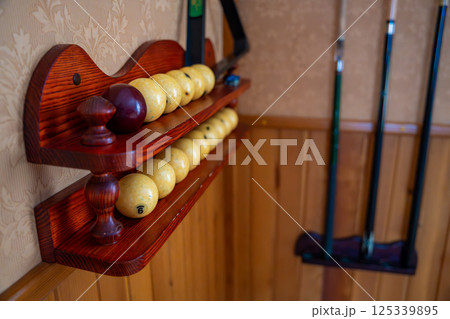 Home billiard setup with white balls, red cue ball, triangle rack, and cues neatly arranged. Concept of indoor recreation and personal hobby space Home billiard setup with white balls, red cue ball, triangle rack, and cues neatly arranged. Concept of indoor recreation and personal hobby space 125339895