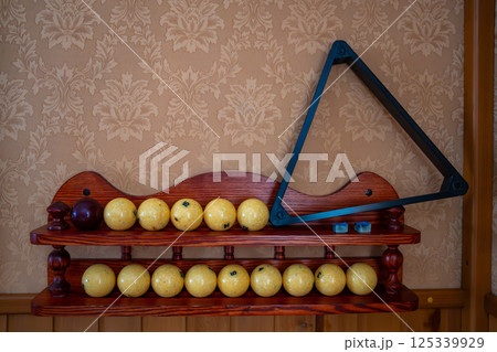 Home billiard setup with white balls, red cue ball, triangle rack, and cues neatly arranged. Concept of indoor recreation and personal hobby space Home billiard setup with white balls, red cue ball, triangle rack, and cues neatly arranged. Concept of indoor recreation and personal hobby space 125339929