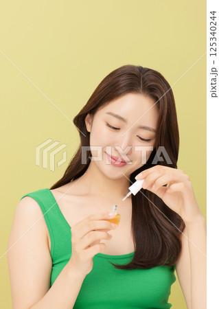 Cropped view of young woman applying nail polish to nails 125340244