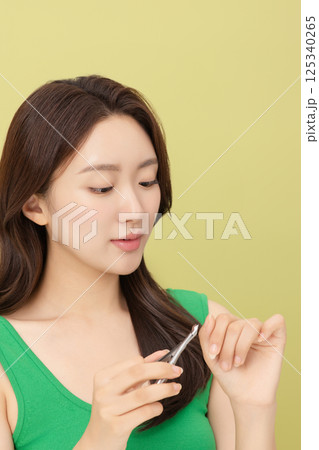 Cropped view of young woman taking care of her nails with nail clippers 125340265