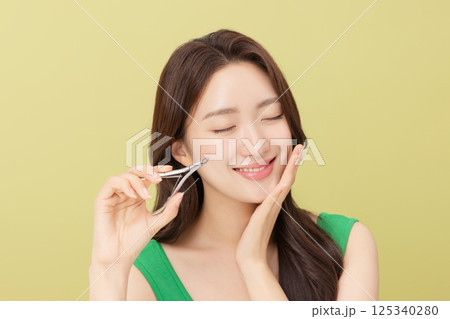 Cropped view of young woman taking care of her nails with nail clippers Cropped view of young woman taking care of her nails with nail clippers 125340280
