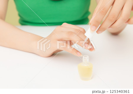 Woman's hands applying nail nourishment Woman's hands applying nail nourishment 125340361