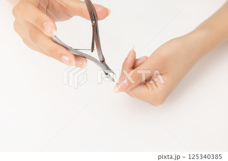 Woman's hands taking care of nail cuticles with nail nippers 125340385