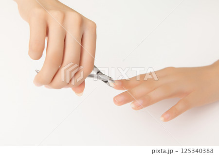 Woman's hands taking care of nail cuticles with nail nippers 125340388
