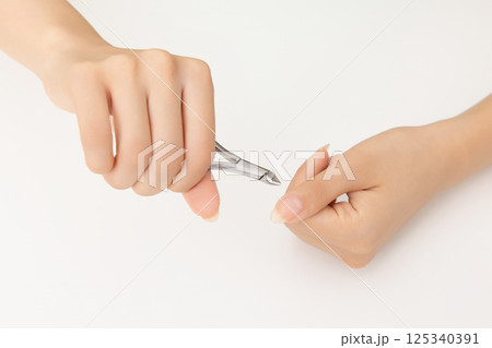 Woman's hands taking care of nail cuticles with nail nippers Woman's hands taking care of nail cuticles with nail nippers 125340391