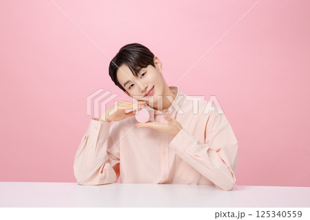 Portrait of a young man posing while holding a cushion Portrait of a young man posing while holding a cushion 125340559