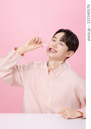 Portrait of a young man posing while holding a cushion Portrait of a young man posing while holding a cushion 125340576