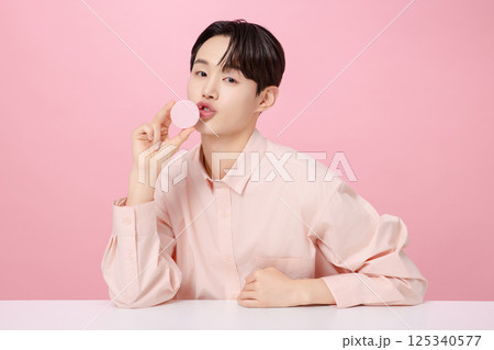 Portrait of a young man posing while holding a cushion Portrait of a young man posing while holding a cushion 125340577