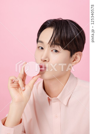 Portrait of a young man posing while holding a cushion Portrait of a young man posing while holding a cushion 125340578