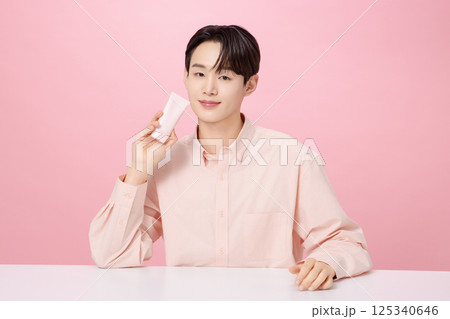 Portrait of a young man posing while holding a tube product 125340646