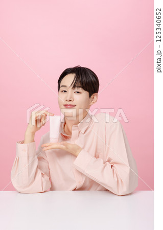Portrait of a young man posing while holding a tube product 125340652