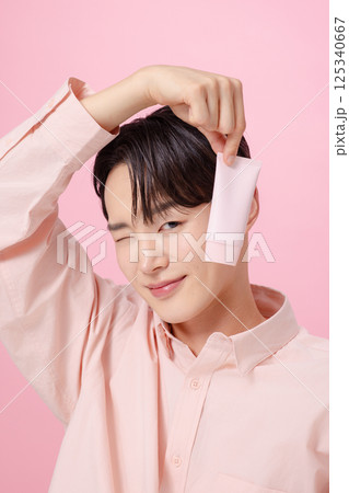 Portrait of a young man posing while holding a tube product Portrait of a young man posing while holding a tube product 125340667