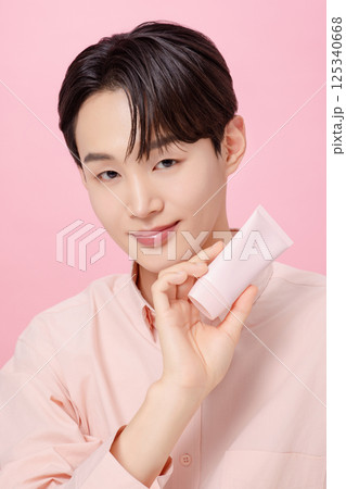 Portrait of a young man posing while holding a tube product Portrait of a young man posing while holding a tube product 125340668