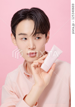Portrait of a young man posing while holding a tube product 125340669