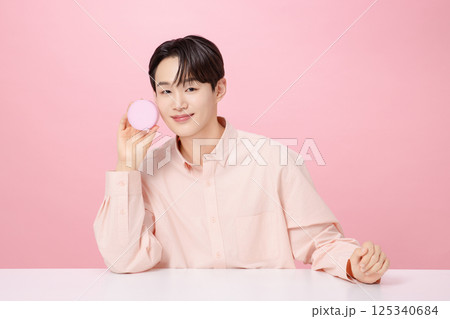 Portrait of a young man posing while holding a cushion 125340684