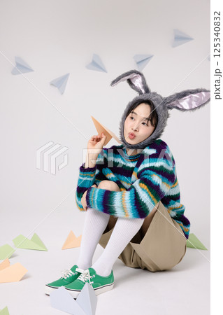 Cropped view of young man wearing bunny hat sitting surrounded by paper airplanes Cropped view of young man wearing bunny hat sitting surrounded by paper airplanes 125340832