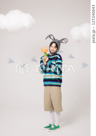 Portrait of a man standing wearing a rabbit hat and holding soap bubbles 125340843