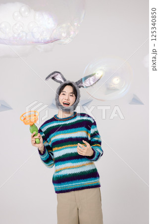 Portrait of a man standing wearing a rabbit hat and holding soap bubbles Portrait of a man standing wearing a rabbit hat and holding soap bubbles 125340850