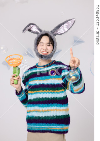 Portrait of a man standing wearing a rabbit hat and holding soap bubbles Portrait of a man standing wearing a rabbit hat and holding soap bubbles 125340851