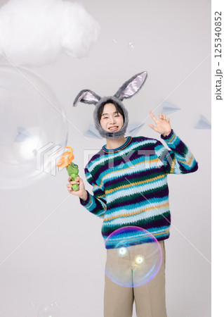 Portrait of a man standing wearing a rabbit hat and holding soap bubbles Portrait of a man standing wearing a rabbit hat and holding soap bubbles 125340852
