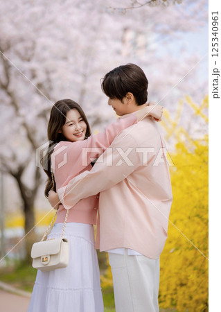 A friendly couple enjoying a date on a street filled with cherry blossoms A friendly couple enjoying a date on a street filled with cherry blossoms 125340961