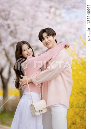 A friendly couple enjoying a date on a street filled with cherry blossoms 125340963