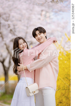 A friendly couple enjoying a date on a street filled with cherry blossoms 125340967