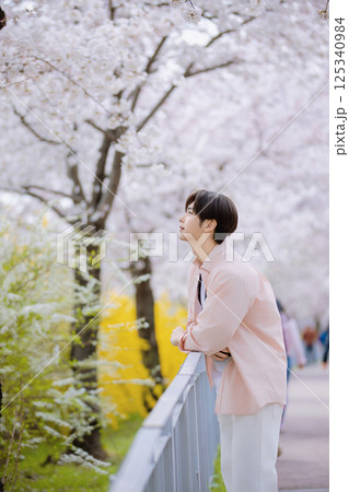 Portrait of a young man looking at cherry blossoms Portrait of a young man looking at cherry blossoms 125340984