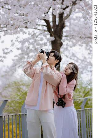 A friendly couple enjoying a date on a street filled with cherry blossoms 125341023