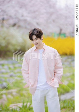 A handsome man taking a photo with cherry blossoms in the background 125341116