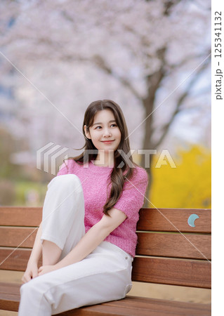 A lovely woman in her 20s sitting on a bench A lovely woman in her 20s sitting on a bench 125341132