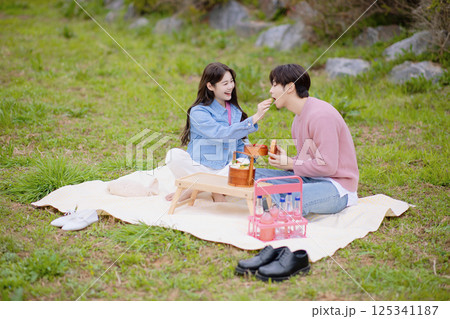 A couple enjoying a date while having a picnic in the park A couple enjoying a date while having a picnic in the park 125341187