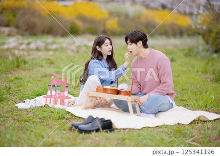 A couple enjoying a date while having a picnic in the park A couple enjoying a date while having a picnic in the park 125341196