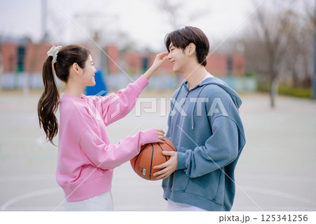 A young couple enjoying a basketball date in the park 125341256