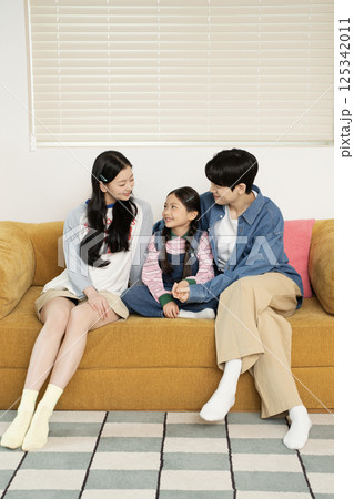 A young couple lovingly looking at their daughter lying on the floor 125342011