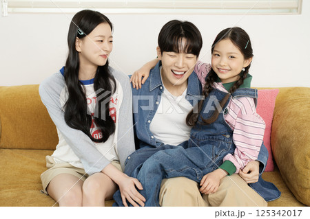 Daughter building domino blocks with her mother and father lying on the sofa 125342017