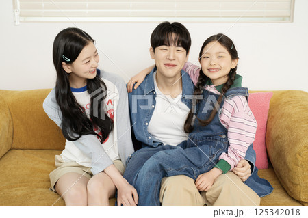 Daughter building domino blocks with her mother and father lying on the sofa 125342018