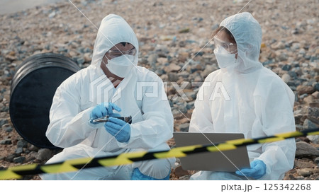 Ecologist sampling water from the river to water quality tester and peek into, Biologist wear protective suit and mask collects sample of waste water from industrial for pH meter, problem environment 125342268