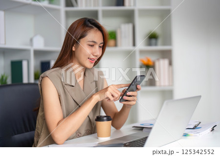Communication and Technology. A young woman engaged in mobile communication while enjoying coffee in her organized workplace. Communication and Technology. A young woman engaged in mobile communication while enjoying coffee in her organized workplace. 125342552