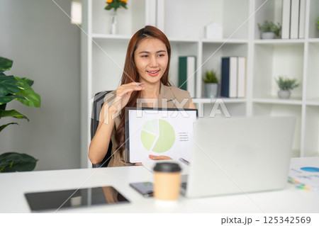 Data Analysis and Remote Work. A woman analyzing results while conducting an online presentation. 125342569